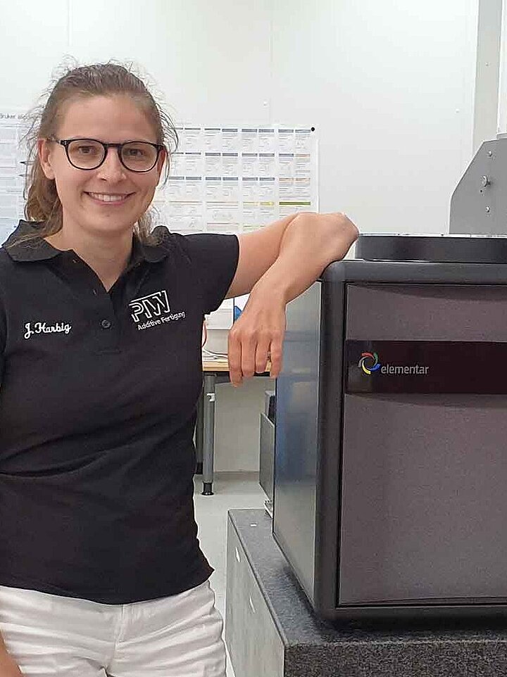 Woman beside an grey metal analyzer in the lab